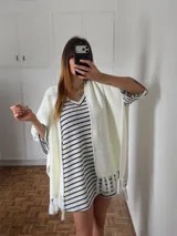 Vestido corto tejido a crochet con rayas horizontales blancas y negras, escote en V y mangas 3/4 acampanadas.