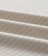 Remera deportiva de manga corta y cuello redondo, color beige claro, con textura acanalada vertical. Presenta detalles reflectantes en los hombros.