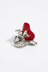 Anillo de metal plateado con forma de rosa roja de resina y hojas plateadas.