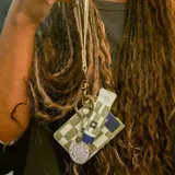 Billetera porta tarjetas vertical de tela con diseño a cuadros en tonos verde y blanco. Incluye un aro metálico para colgar.