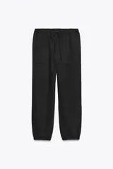 Pantalón jogger color gris claro, de tiro alto con cintura elástica ajustable con cordones, bolsillos delanteros y traseros con solapa, y puños elásticos en el bajo.