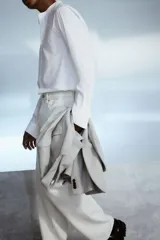 Camisa blanca de corte estándar, con cuello mao, tapeta clásica, canesú en la espalda, mangas largas con puños abotonados y bajo redondeado.