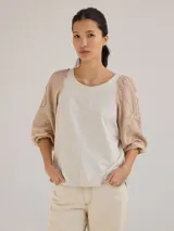 Remera gris de algodón con mangas color beige con bordados de líneas en blanco, amarillo y gris.