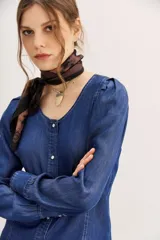 Camisa azul de tencel con calce entallado, cuello redondo, mangas largas con frunces en los hombros y costuras a contratono.