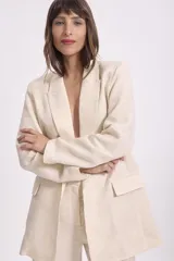 Blazer color crema con textura de lurex, solapas clásicas, corte recto y bolsillos delanteros.