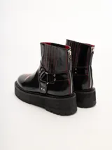 Botas de cuero color bordó con elástico en los laterales, detalle de bordado en hilo rojo en la puntera y hebillas con apliques metálicos. Plataforma de goma negra de 5 cm de altura.