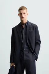 Blazer azul marino de lino con corte regular fit, cuello con solapas de muesca, manga larga con puños abotonados, bolsillo de vivo en el pecho, bolsillos de solapa en la cadera, bolsillo interior, aberturas en la espalda y cierre frontal de botonadura.