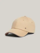 Gorra de béisbol clásica de seis paneles color beige, confeccionada en algodón. Presenta un pequeño logo rectangular de Tommy Hilfiger en la parte delantera y ribetes con los colores distintivos de la marca en el borde de la visera.