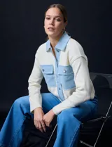 Campera combinada de punto color crema con detalles en denim celeste. Tiene cuello con solapa, cierre frontal con botones metálicos, bolsillos delanteros y corte recto.