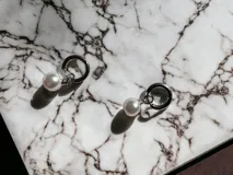 Par de aros plateados con dije de perla colgante.