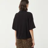Camisa negra de lino con corte holgado, cuello clásico, manga corta y cierre frontal con botones.