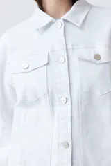 Campera de jean blanca con cuello clásico, bolsillos con solapa abotonados en el pecho y cierre frontal con botones metálicos. Corte recto.