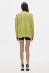 Sweater tejido color borgoña con cuello alto, corte oversize y mangas largas con detalle de trenzas verticales.