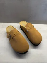 Suecos color marrón claro con hebilla ajustable y suela de goma negra.