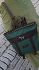 Mochila pequeña color borgoña con detalles en cuero marrón, asa de mano y correas ajustables.