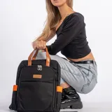 Mochila negra con detalles en naranja y marrón. Tiene dos asas cortas marrones en la parte superior y dos bolsillos laterales color naranja.