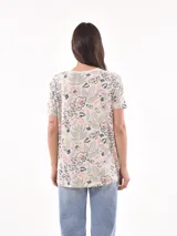 Remera blanca con estampado de flores y hojas en tonos pastel.