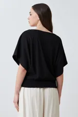 Blusa negra con textura amasada, de mangas cortas y corte holgado.