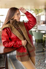 Chaqueta bomber de cuero color marrón, con cuello de piel sintética roja, cierre frontal con cremallera y bolsillos laterales.