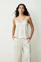 Blusa color crudo con lunares dorados, breteles finos y escote en V con detalle de encaje.