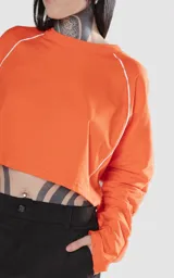 Remera corta naranja de manga larga con ribete blanco en las mangas.