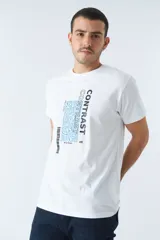 Remera color ocre con cuello redondo y mangas cortas. Estampado frontal con la palabra "CONTRAST" en mayúsculas y un diseño abstracto en blanco y negro.