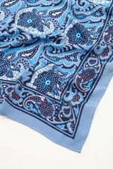 Pañuelo cuadrado de poliéster color celeste con estampado de motivos geométricos y florales en tonos azules, grises y borgoña.
