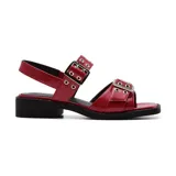 Sandalia roja de charol con hebillas plateadas y suela de goma negra.