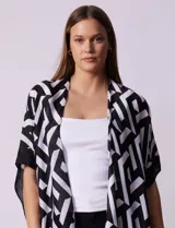 Kimono tejido con estampado geométrico en blanco y negro, ruedo con borlas y composición 100% poliéster.