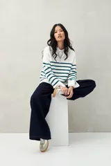 Sweater blanco con rayas horizontales azul verdoso, cuello alto con cierre metálico y terminaciones acanaladas.