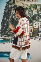 Cardigan oversized de tejido jacquard color crema con diseño de cuadrados en marrón y detalles bordados. Tiene cuello en V, cierre con botones, mangas largas y bolsillos frontales.