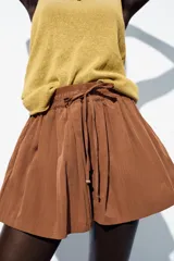 Bermuda color marrón con cintura elástica ajustable con cordones y bolsillos delanteros.