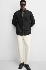 Pantalón negro de corte cropped, con cintura elástica ajustable con cordón, bolsillos laterales y traseros de vivo. El bajo tiene terminación con vuelta.