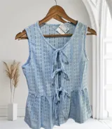 Blusa sin mangas de encaje con detalle de lazo en el escote y corte peplum.