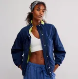 Chaqueta tipo bomber azul marino, con cuello alto y forro interior de piel sintética color verde lima. Presenta cierre frontal con broches y cremallera, y puños y cintura elásticos.