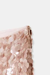 Falda corta de corte recto, completamente cubierta de lentejuelas redondas en tonos plateados y marrones/bronce. Posee forro interior y cierre lateral oculto.