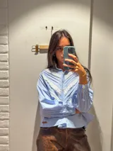 Camisa blanca de mangas largas con cuello alto y detalles de encaje.