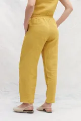 Pantalón de lino color marrón, de corte recto y tiro alto, con cintura elástica y bolsillos laterales.