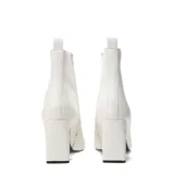 Botas de caña corta en color blanco con punta cuadrada y taco bloque. Cuentan con un detalle en contraste negro en la parte interna del taco y un tirador posterior para facilitar el calce.