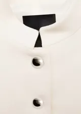 Chaqueta corta color crema con cuello mao y cierre frontal con botones joya.