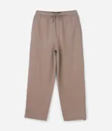 Pantalón baggy color beige, confeccionado en algodón con felpa. Presenta cintura elástica con cordón ajustable, bolsillos delanteros y un bolsillo trasero. El bajo es ajustable con elástico.