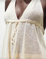 Top tejido color crudo, con breteles finos y corte holgado con volados en el ruedo.