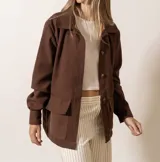 Chaqueta marrón con cuello camisero, cierre frontal con botones, mangas largas y bolsillos de parche en el pecho.