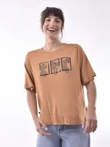 Remera color ocre con estampado de tres leopardos enmarcados y texto inferior.