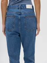 Pantalón de jean azul de tiro alto y corte oxford con apliques metálicos en bolsillos y laterales.