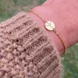 Pulsera dorada con dije circular con el símbolo de la paz formado por pequeñas circonitas.
