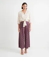 Pantalón pantacourt de viscosa color lila con estampado de pequeños cuadrados blancos. Tiene pinzas delanteras, bolsillos laterales y cierre con botones.