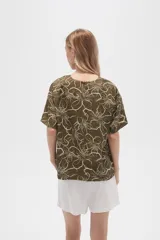 Blusa verde militar con estampado de flores blancas, de viscosa, corte holgado, cuello redondo y mangas cortas.