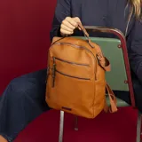 Mochila color beige de símil cuero con doble apertura superior con cierre. Incluye dos bolsillos al frente con cierres metálicos, asa rígida de mano y correa de galón. En la espalda correas de galón regulables.