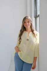 Blusa color amarillo pálido con cuello en V, manga 3/4 y calados con forma de paisley.